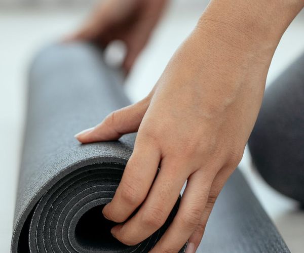 A rolled-up yoga mat and a water bottle, ready for a class.
